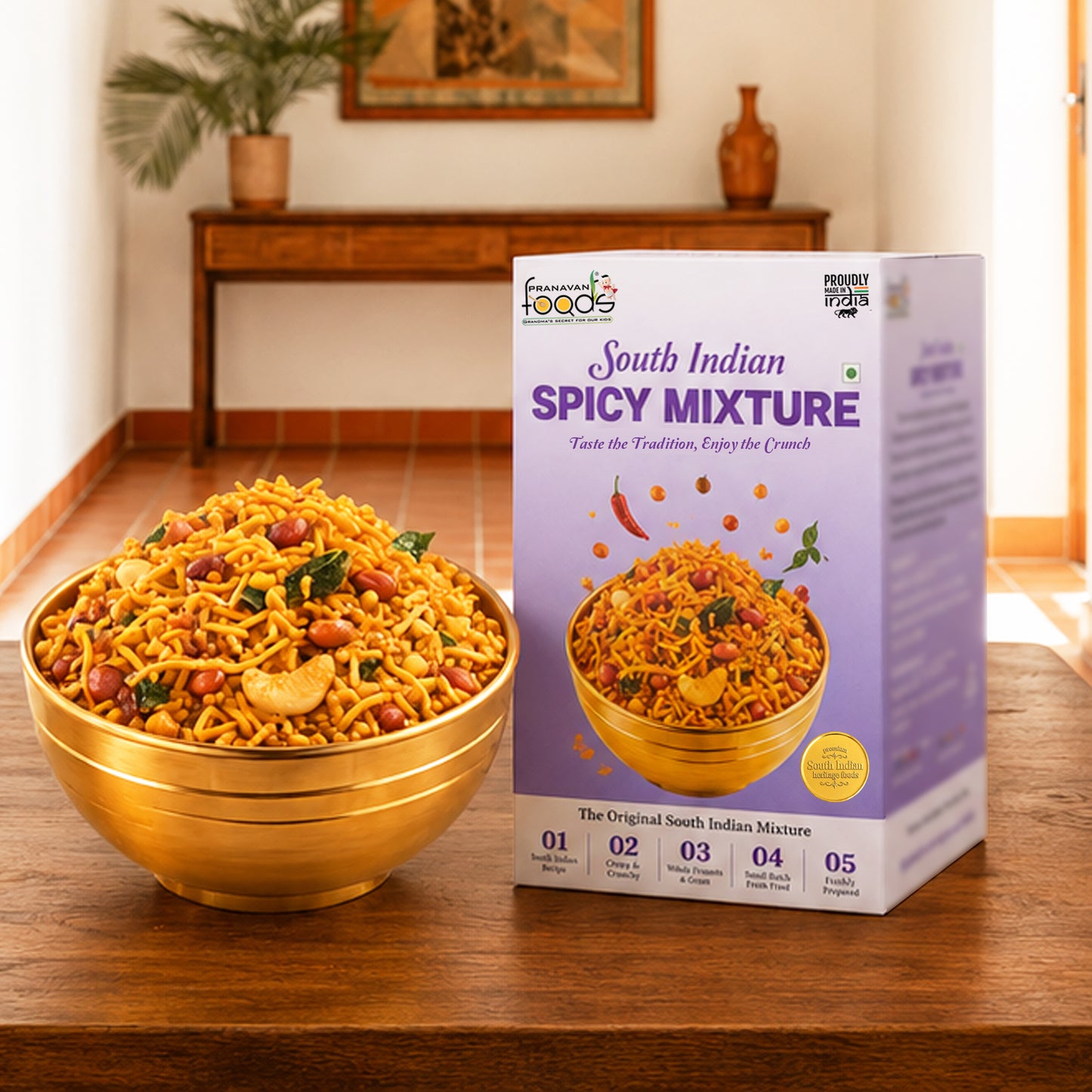 A bowl of South Indian Spicy Mixture snack mix is shown next to its retail packaging box on a wooden table, with a warm, blurred indoor background.