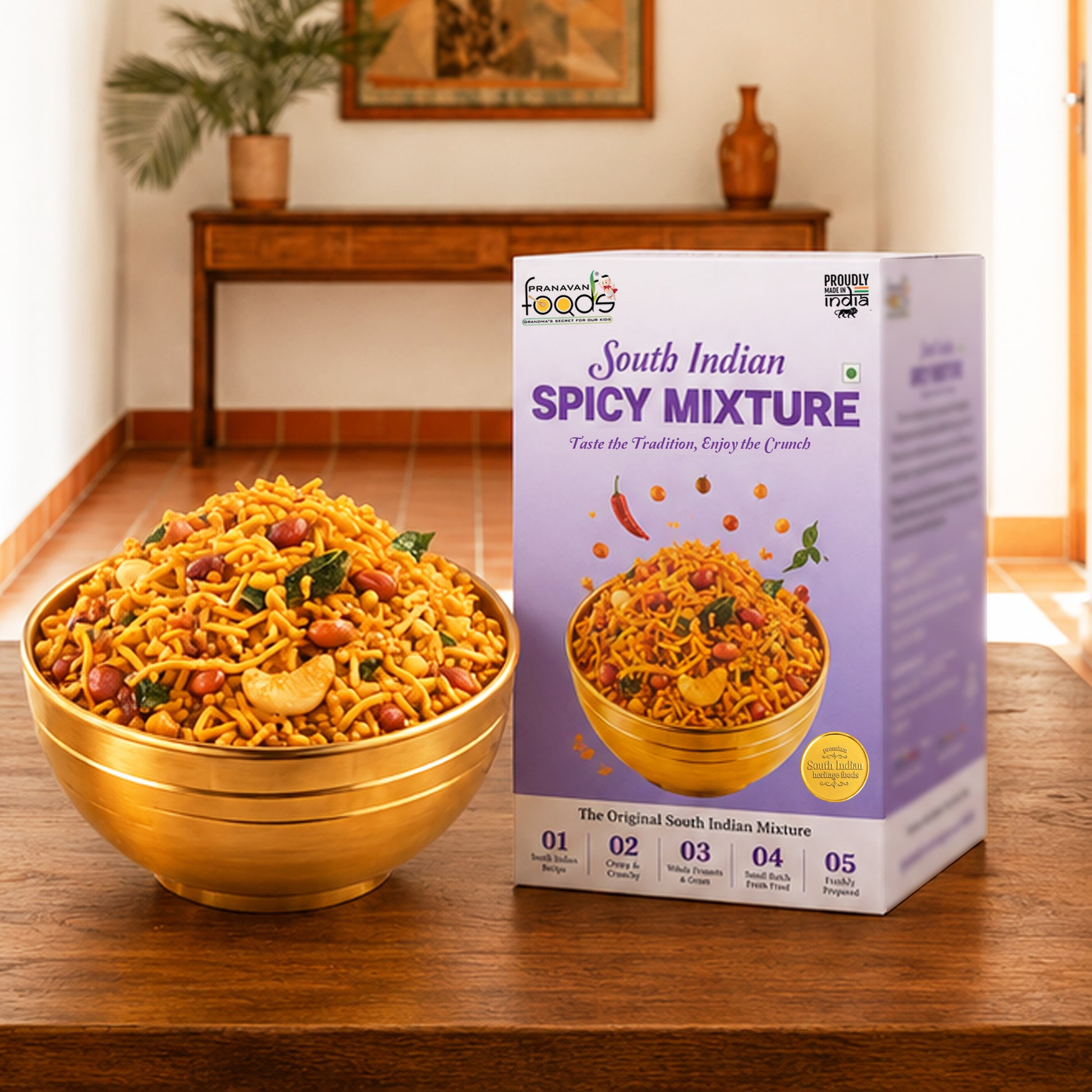 A bowl of South Indian Spicy Mixture snack mix is shown next to its retail packaging box on a wooden table, with a warm, blurred indoor background.
