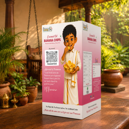 A boxed snack product labeled 'Coconut Oil Banana Chips' stands on a wooden table in a real outdoor porch setting with plants and hanging decor visible in the background. The box is predominantly pink and white with a cartoon child holding banana chips, product text, a QR code, and a Pranavan approval seal.