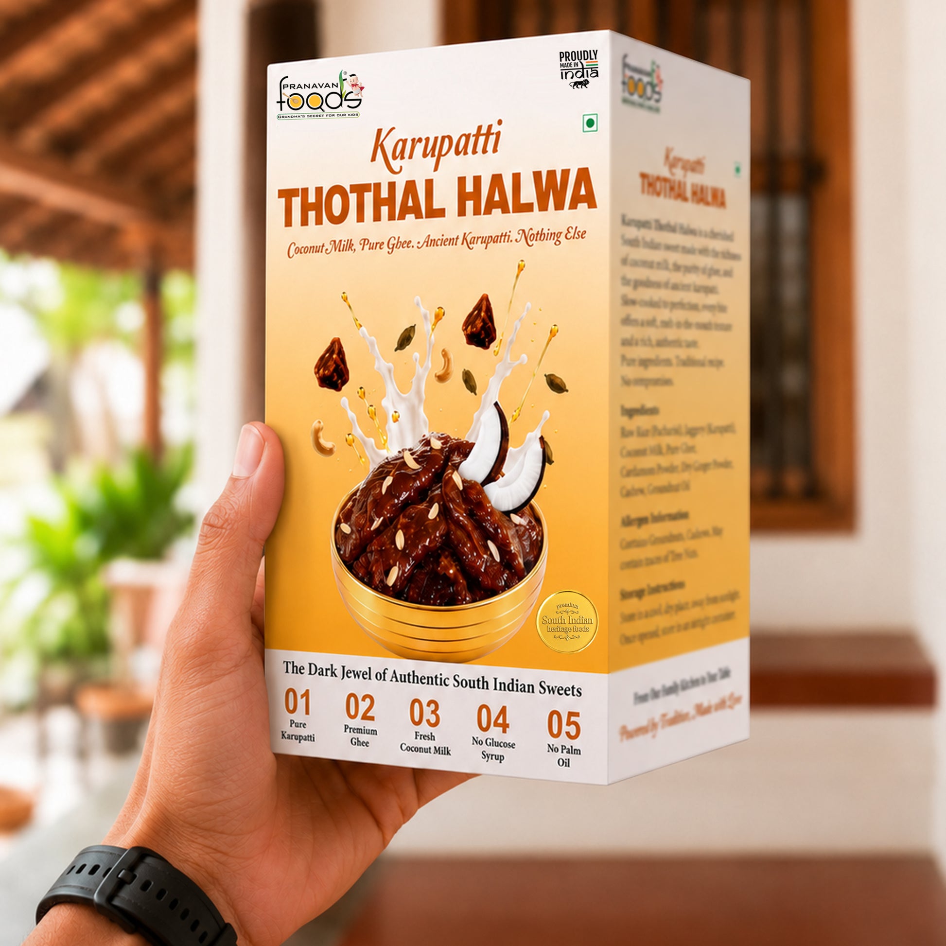 A hand holding a box of Karupatti Thothal Halwa from Karupatti Salama, with a blurred indoor background showing warm lighting and plants.