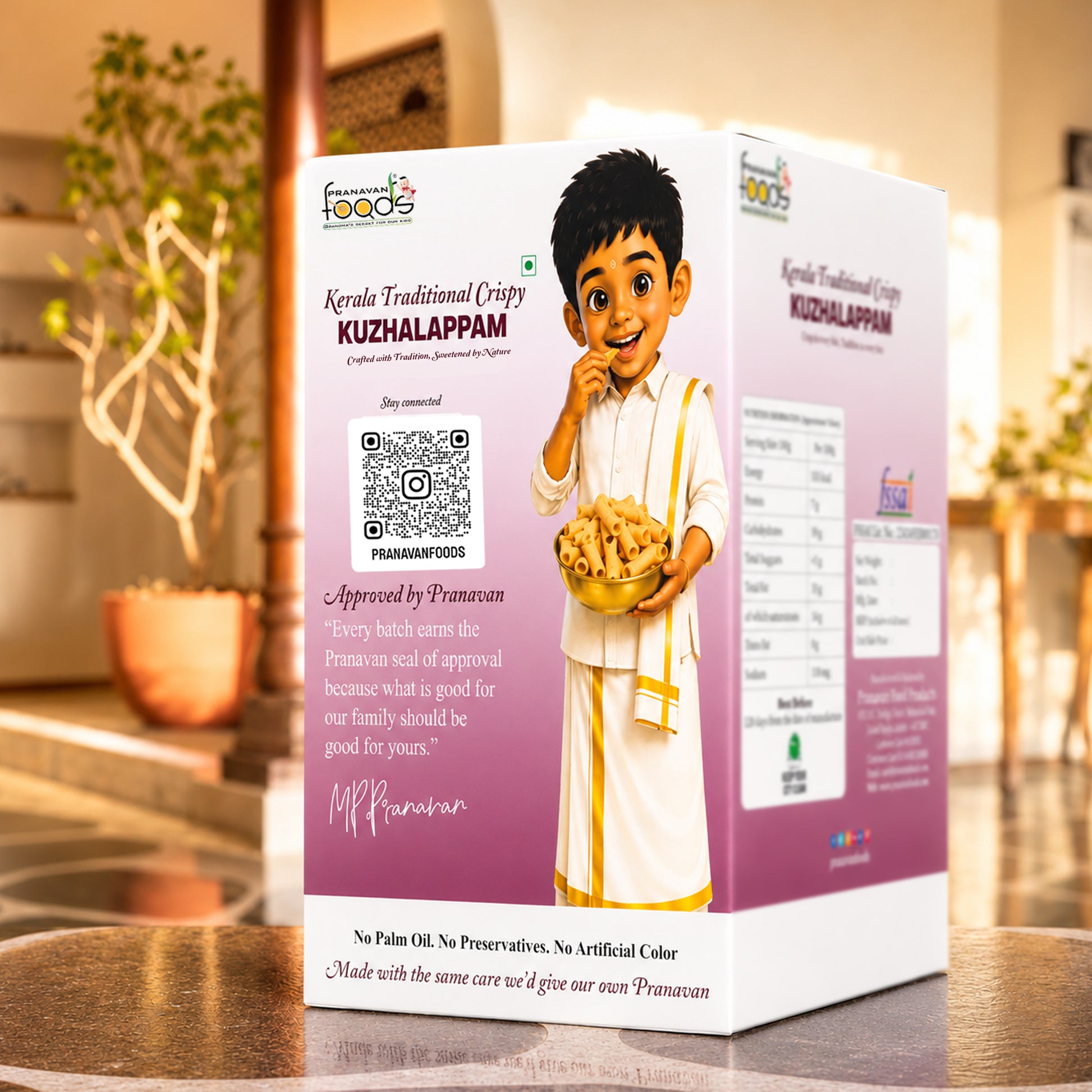 A boxed food product labeled 'Kerala Traditional Crispy Kuzhalappam' stands on a wooden table in a warm indoor setting. The box is predominantly white and pink/lilac with an illustrated child in traditional clothing holding a bowl of appam, plus product details, a QR code, and approval text.